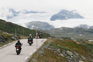 Norveç 'teki karlı dağ tepelerine doğru giden bir grup motosikletli..