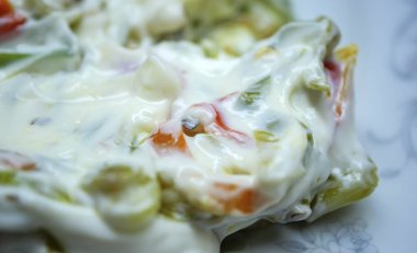 İçinde Purslane ya da salatalık gibi doğranmış yeşil sebzeler bulunan yoğun yoğurt salatası kremalı beyaz kıvamını gösterir.