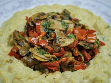 Kızarmış mantar ve kırmızı biber karışımıyla kaplı kremalı humus ya da patates püresi yatağını kapat.