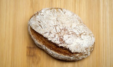 Kaba bir oval ekmek somunu, altın kahverengi kabuktaki beyaz un desenini gösteriyor. Sanatçının pişirme yöntemlerinin tipik bir örneği..