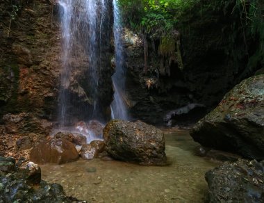 Şelalenin dibindeki dingin su havuzu ulusal parkın sessiz bir köşesindeki kayalık çevreyi ve orman ağaçlarını yansıtıyor.