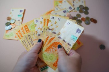 Elleri nakit tutuyordu. Arjantin pezosu 1000 banknot ve bozuk para.