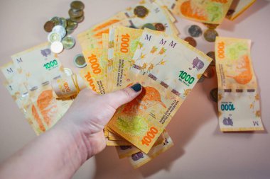 Elleri nakit tutuyordu. Arjantin pezosu 1000 banknot ve bozuk para.