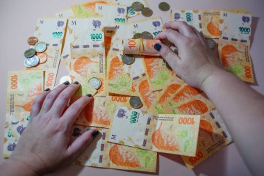 Elleri nakit tutuyordu. Arjantin pezosu 1000 banknot ve bozuk para.