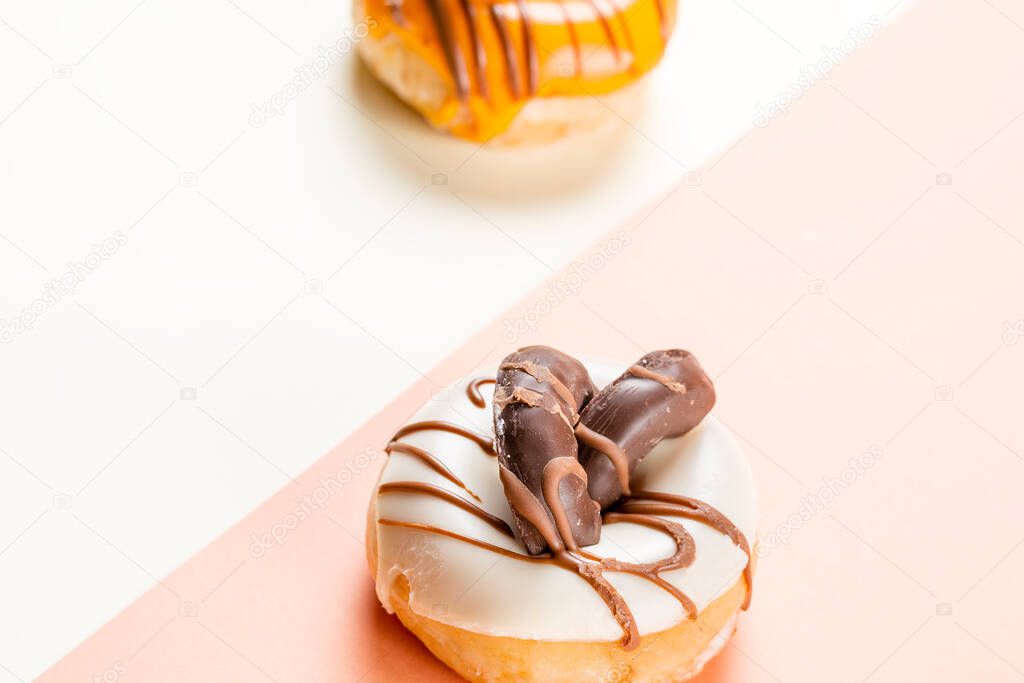 Close-up of a white donuts with chocolate chip cookies and a side of unfocused cream donuts.The photograph is taken in horizontal format and has a two-color background.
