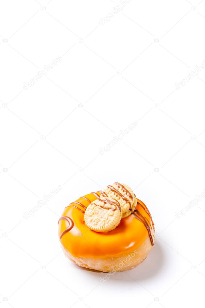 Photograph of a cream donuts painted with chocolate and with cookies on a white background.The photo is taken in vertical format and has copy space.