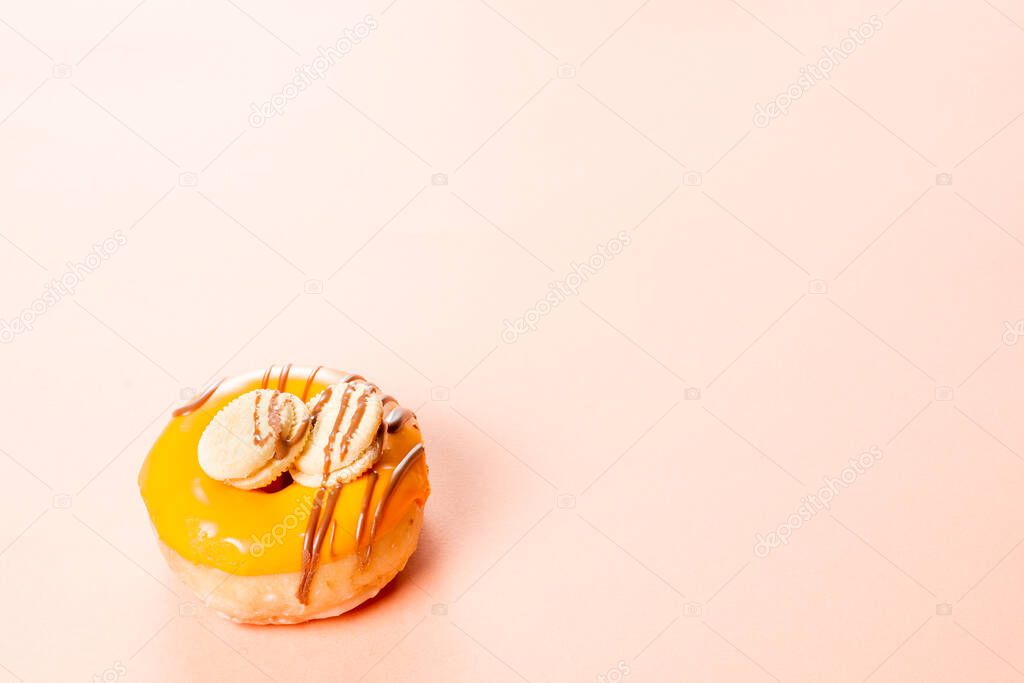 Photograph of a cream donuts decorated with two cookies and drawn with chocolate.The photo is taken horizontally on a cream-colored background.The photo has copy space.