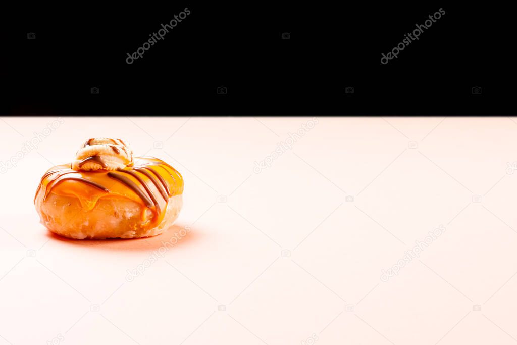 Horizontal photograph of a cream donuts on a light brown cardboard and a black background.The photograph has enough space to write text or whatever you want.