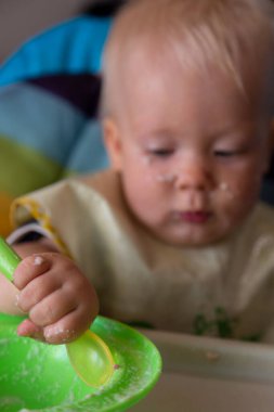 Küçük çocuk kaşıkla yemek yiyor.