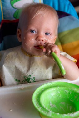 Küçük çocuk kaşıkla yemek yiyor.