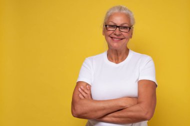 Canlı bir gülümsemesi olan güzel, yaşlı bir bayan doğrudan kameraya bakıyor.