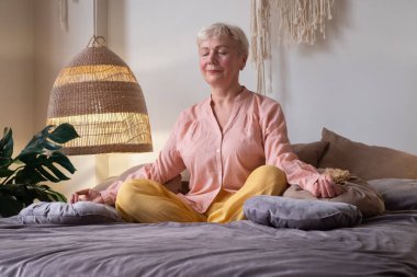 Beyaz kadın içeride yoga yaparken meditasyon yapıyor..