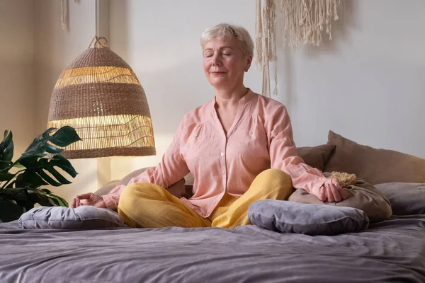 Старша біла жінка, що медитує практикує йогу в приміщенні . — стокове фото
