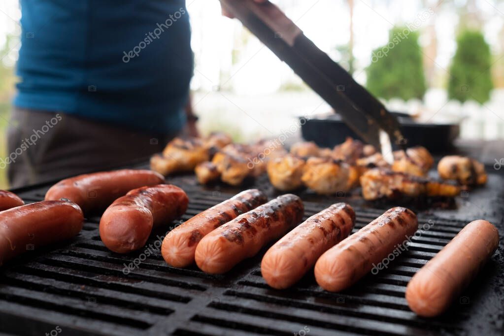 Sausages grilling outdoors on a gas barbecue grill.