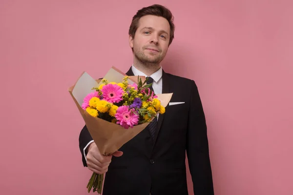 Leende man med en bukett blommor gör ett förslag. — Stockfoto