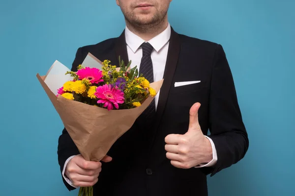 Hombre con hermoso ramo de flores mostrando el pulgar hacia arriba. — Foto de Stock