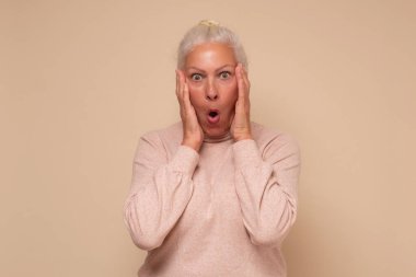 Vay canına. Ağzı açık ve elleri yanında tutarken heyecanlı görünen son sınıf bir kadının portresi. Stüdyo çekimi