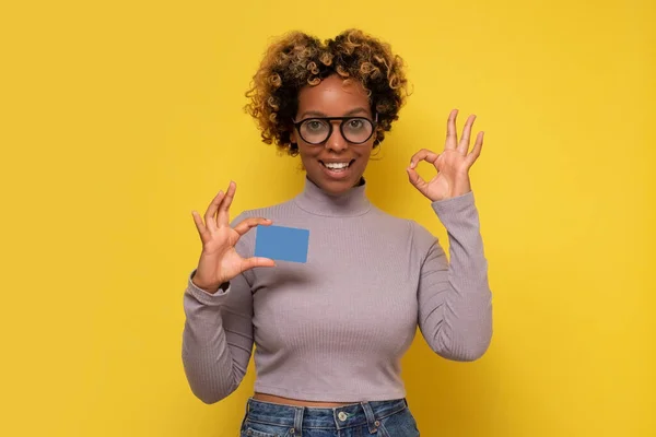 Sorrindo Afro Americana Segurando Cartão Crédito Gestos Isolado Fundo Amarelo — Fotografia de Stock