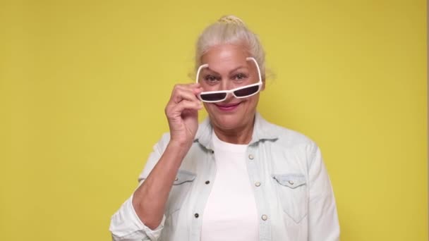 Senior femme en lunettes de soleil noires sur fond jaune — Video