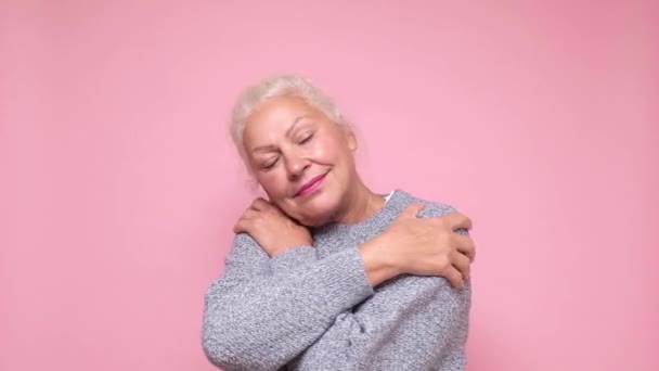 Senior kvinna hålla händerna på axlarna kramar sig själv, med glada fridfulla leende — Stockvideo