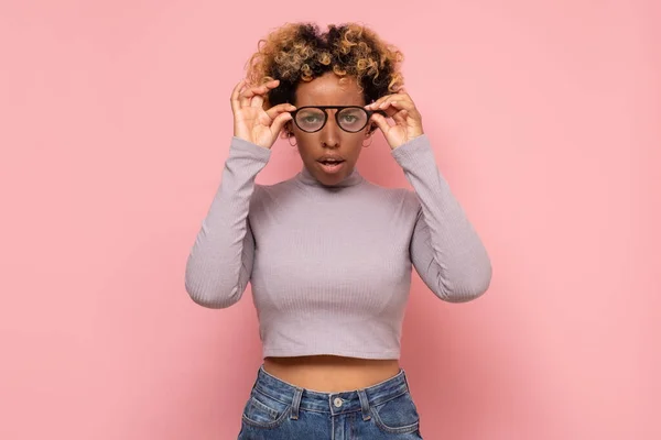 Afrikanische junge Frau blickt durch eine neue Brille und bemerkt interessante Informationen. — Stockfoto