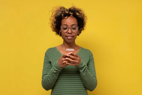 Africano jovem mulher tipos mensagem de texto no telefone celular, goza de comunicação on-line — Fotografia de Stock