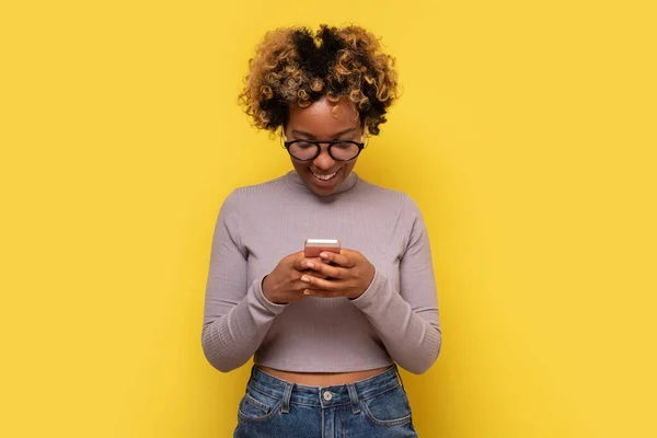 Африканська молода жінка друкує повідомлення на мобільному телефоні, користується онлайн-спілкуванням. — стокове фото