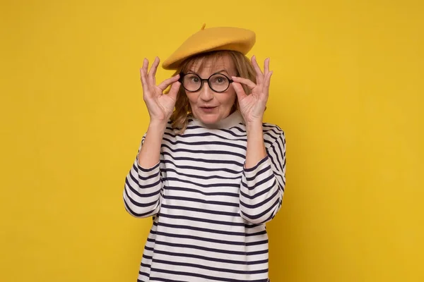 Женщина средних лет в жёлтой шляпе и очках улыбается, глядя в камеру. — стоковое фото