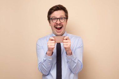 Akıllı telefonda oynayan gülümseyen beyaz bir adam..