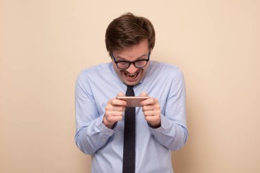 Akıllı telefonda oynayan gülümseyen beyaz bir adam..