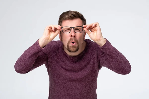 Homem caucasiano segurando óculos, olhando através deles em detalhes. — Fotografia de Stock