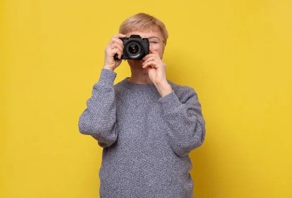 Dojrzałe kobieta fotograf z ksero na twarzy stojącej na żółtym tle. — Zdjęcie stockowe