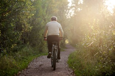 Dışarıda bisiklete binen yaşlı beyaz bir adam.