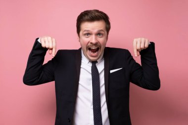 Gülümseyen genç işadamı pembe duvarda soyutlanmış bir şekilde.