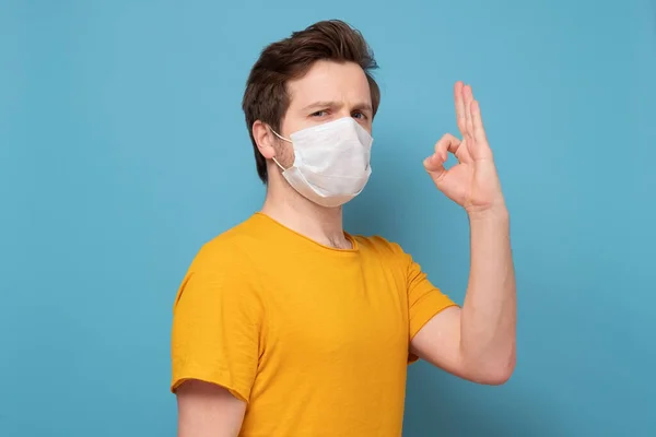 Hombre guapo en máscara médica mostrando gesto bien. —  Fotos de Stock