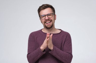 Sakallı ve gözlüklü gülümseyen genç adam kameraya bakıyor..