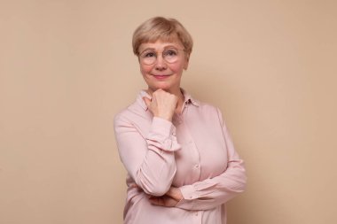 Kameraya gülümseyen gözlüklü yaşlı beyaz kadın..