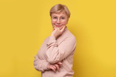 Kameraya gülümseyen gözlüklü yaşlı beyaz kadın..