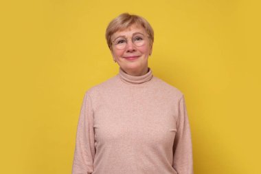 Kameraya gülümseyen gözlüklü yaşlı beyaz kadın..