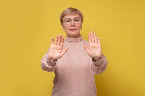 Vážná dospělá žena stojící s nataženou rukou ukazující stop gesto. — Stock fotografie