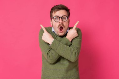 Kafası karışmış genç adam iki farklı yönü işaret ediyor, hayatta hangi yöne gideceğinden emin değil.