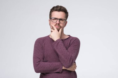 Senin için yeni fikirler üretiyorum. Düşünceli bir genç adam çenesinden tutarak kameraya bakıyor.