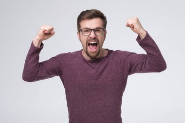 Heyecanlı adam kazanıyor, kollar havada, yumruklar havada başarıyı kutluyor..