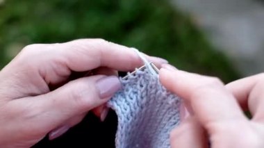 Olgun beyaz kadın elleri bir eşarp örüyor..