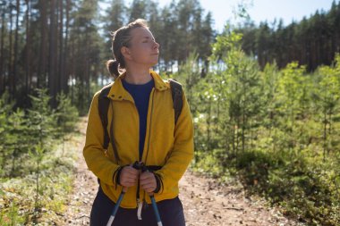 Ormanda yürüyen özel yürüyüş sopaları kullanan bir kadın..