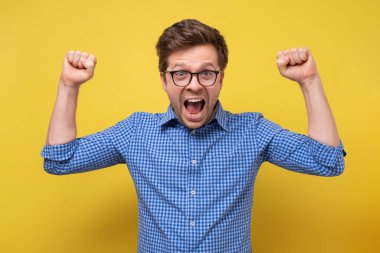 Yakışıklı, heyecanlı, mutlu, gülümseyen, kameraya bakan, el ele tutuşan, el kaldıran, el kaldıran adam..