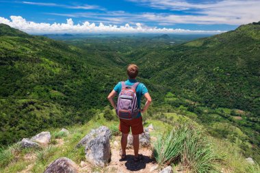 Erkek turist harika bir manzarayla dağın tepesinde duruyor..