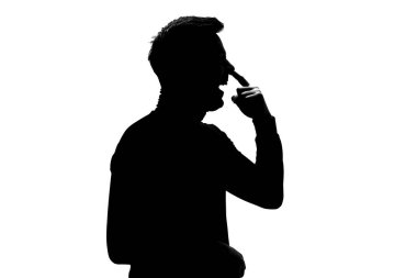 Genç adamın komik yüzüyle burnunu delen silueti. Kötü alışkanlık. Stüdyo çekimi