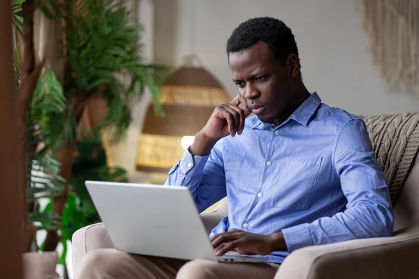 Young serious african man typing on laptop at home Stock Photo