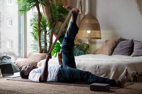 Young sporty african man working out at home , warming up using yogic belt Stock Photo